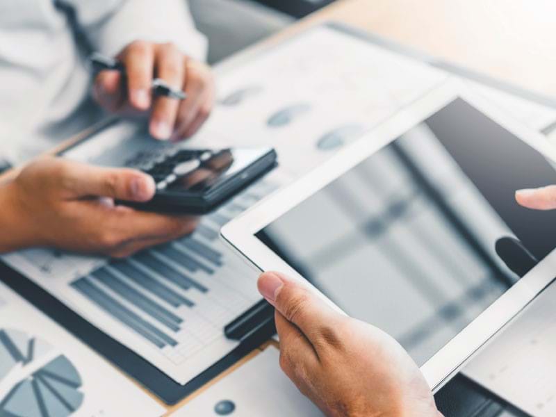 Hands using a tablet and a calculator