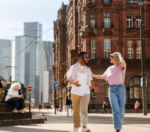 Two people walking through a busy square in Manchester city centre