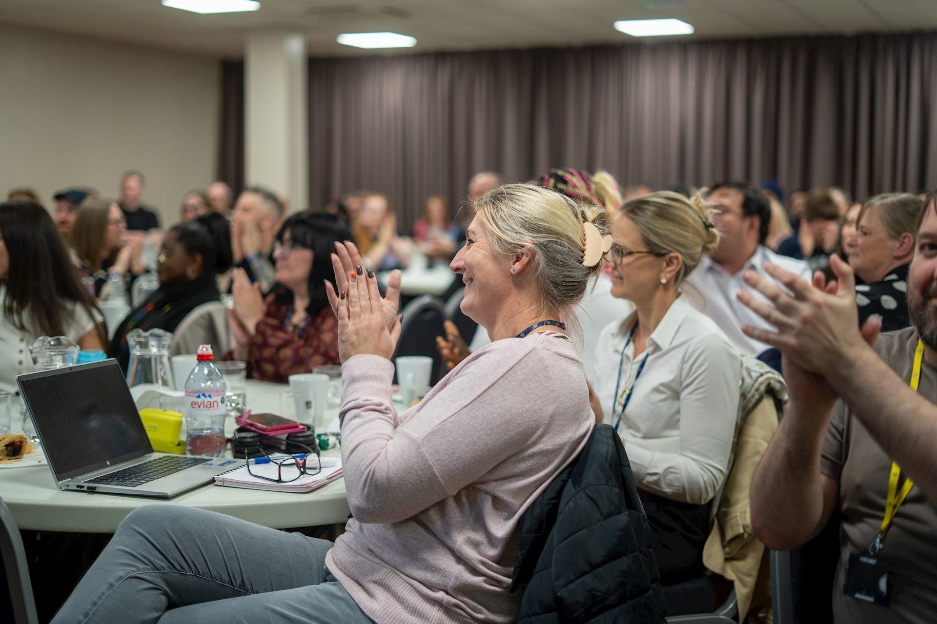 A room full of colleagues attending an event giving a round of applause