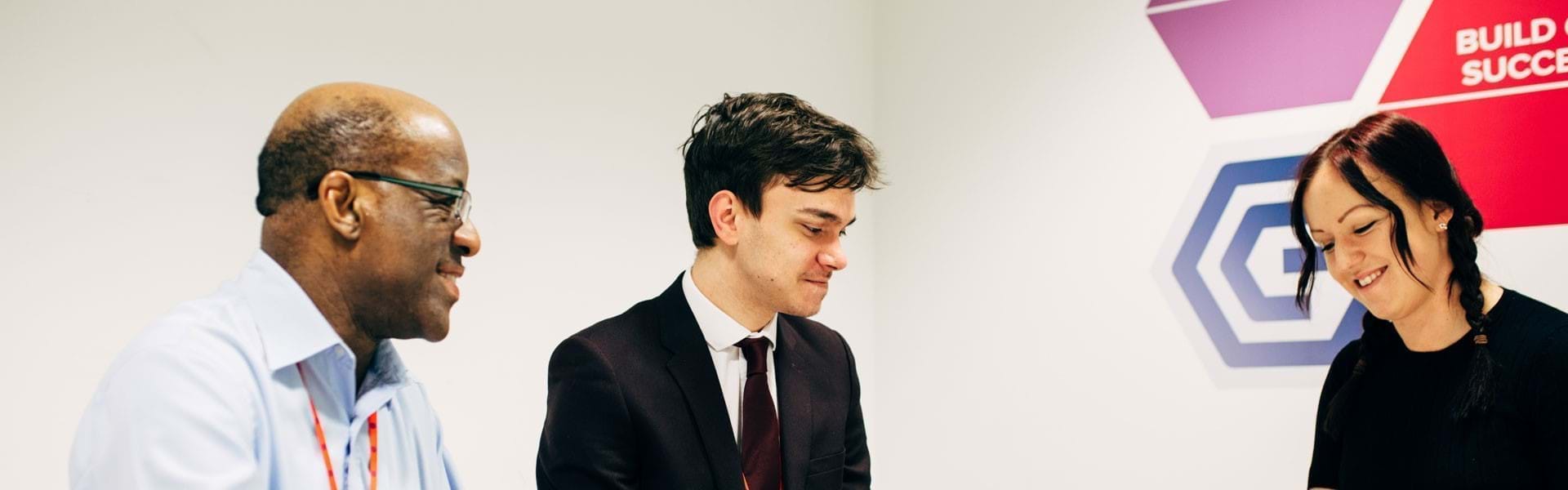 Image of 3 colleagues in a meeting with the Growth Company branding behind them.