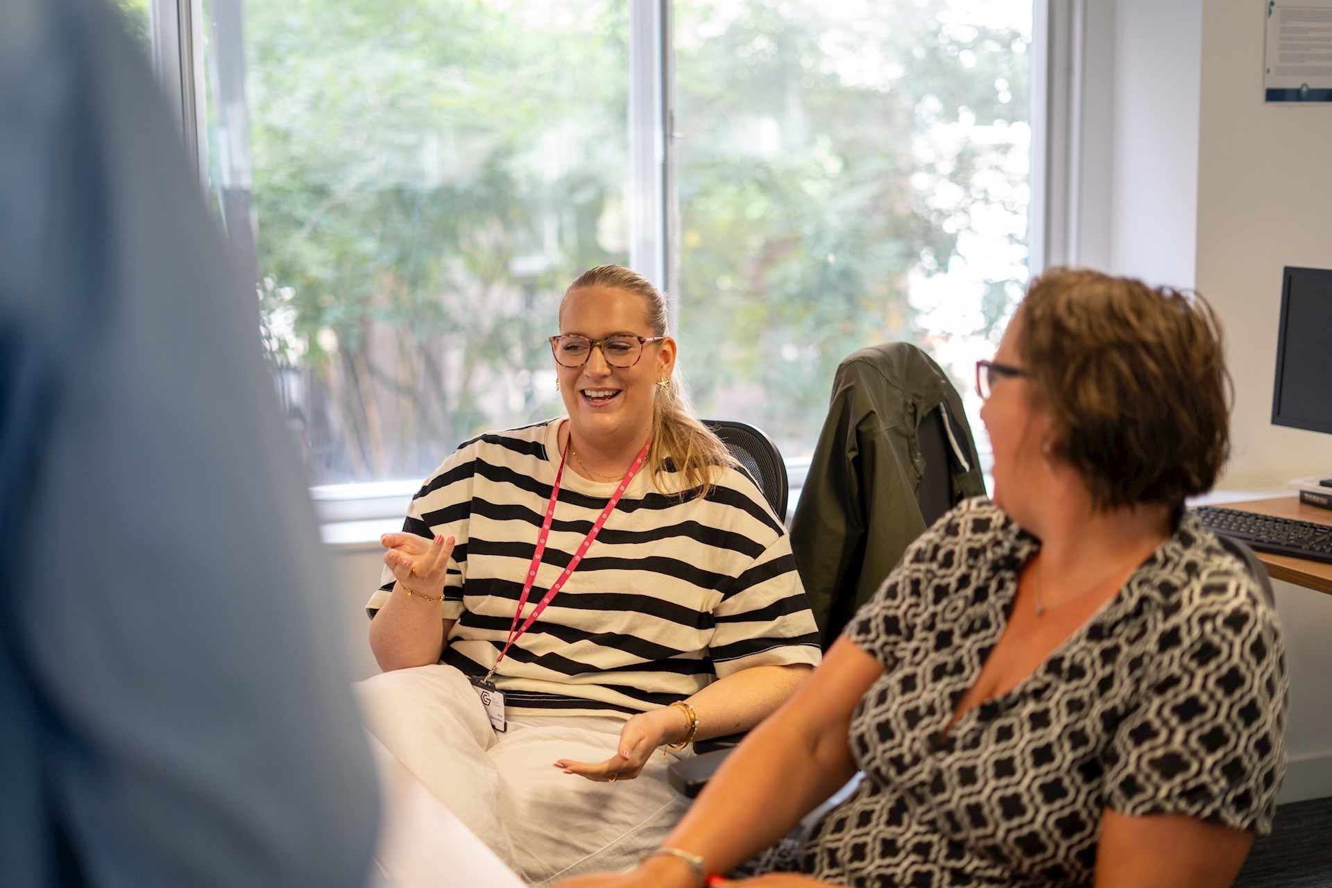 Two colleagues sitting next to each other having a conversation and laughing