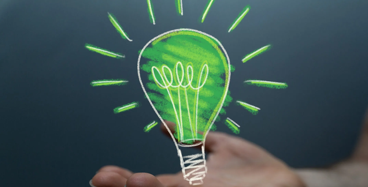 Image of drawn green lightbulb resting on someone's hand 