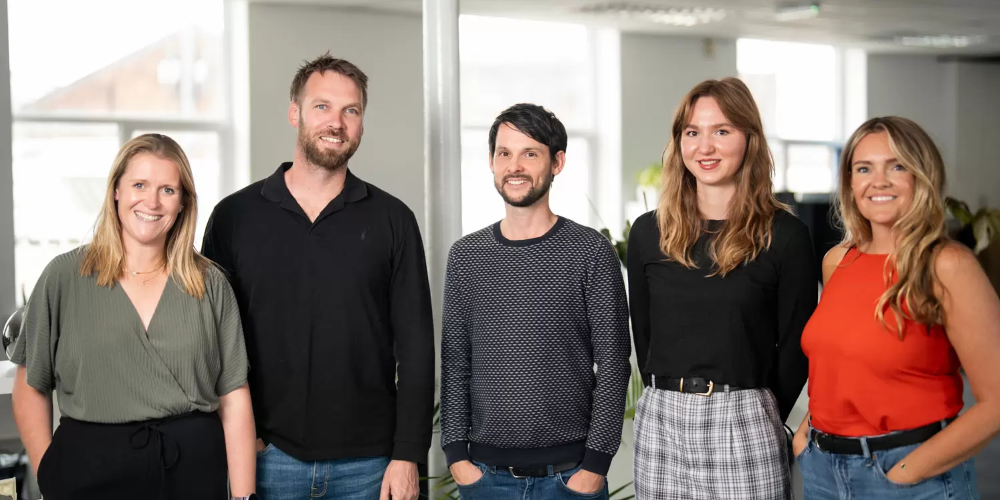 Group photo of 5 members of the NPD team smiling in an office