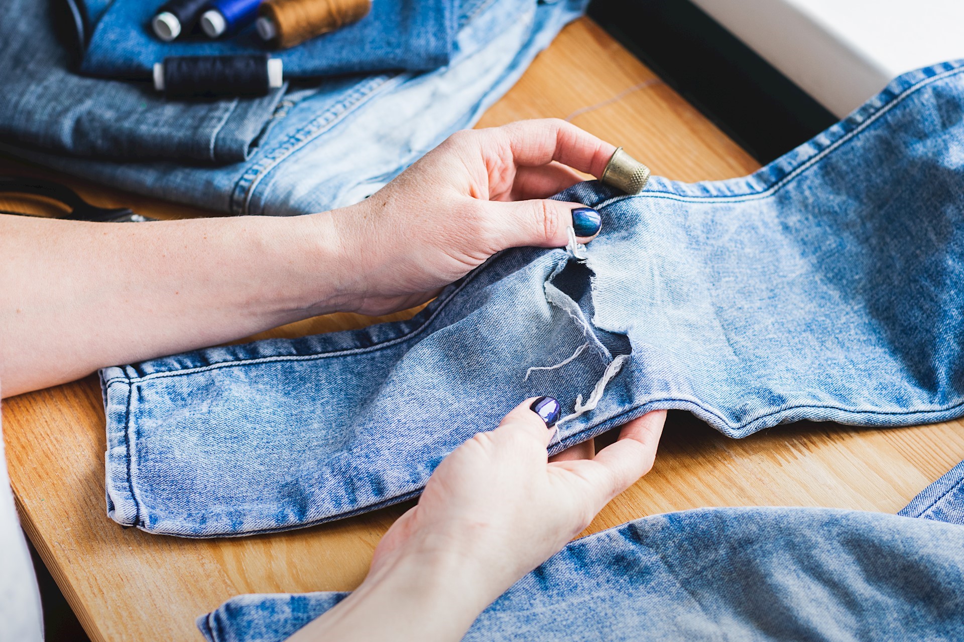 Image of someone repairing a hole in a pair of jeans, Natalia Khimich vit Getty