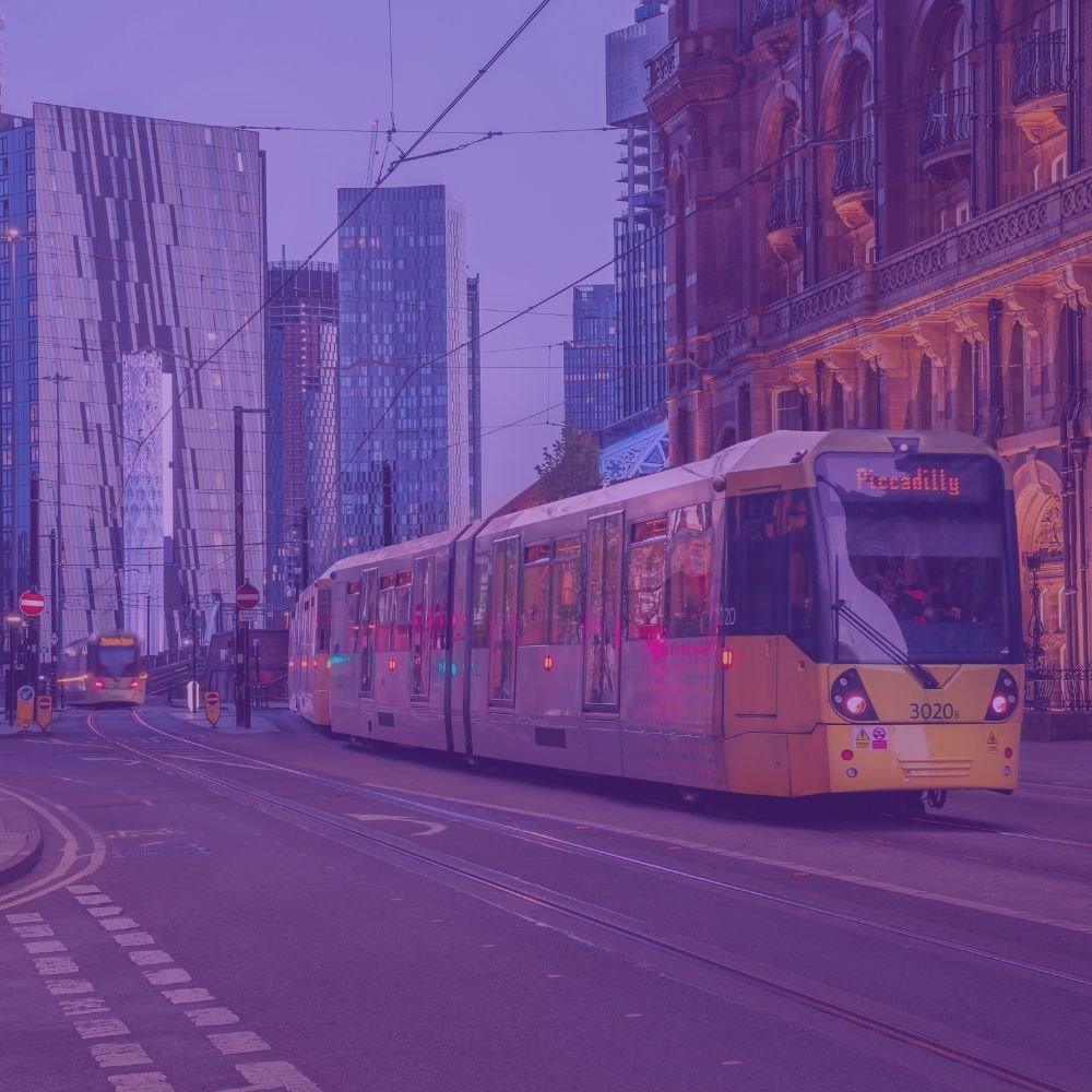 Yellow Metrolink tram driving through Manchester City Centre with a purple tint 