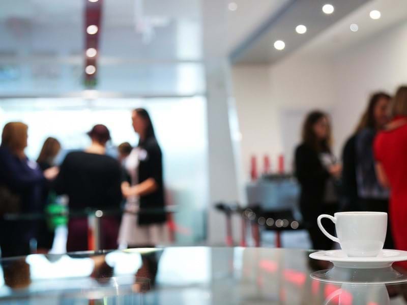 Blurred image of people chatting over refreshments