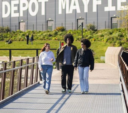 A group of friends walking across a bridge in a park in Manchester